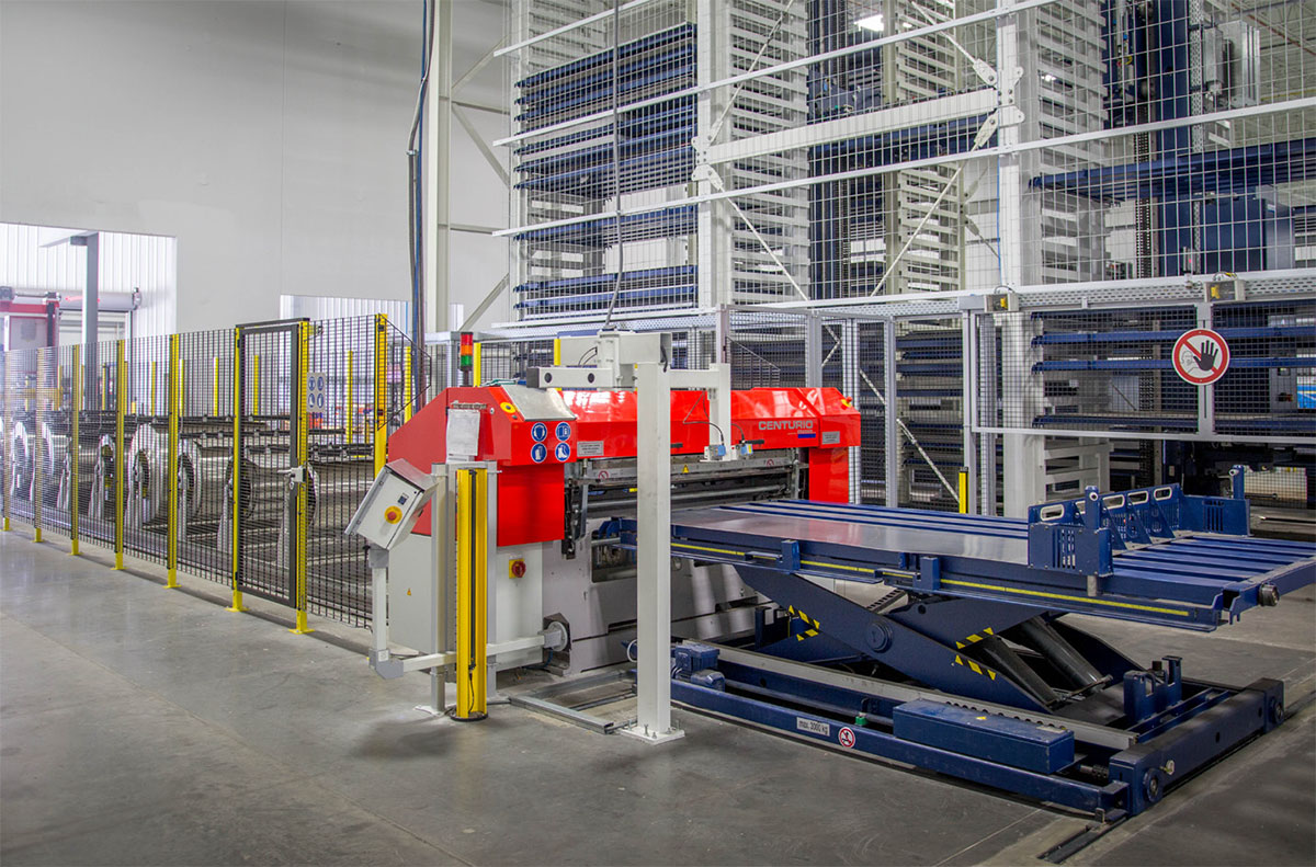 Picture: STOPA COMPACT, A slitting machine cuts the thin sheet metal delivered in coils and pushes the sheets onto a flat pallet, which a scissor lift table then transports into the STOPA COMPACT automatic storage system.